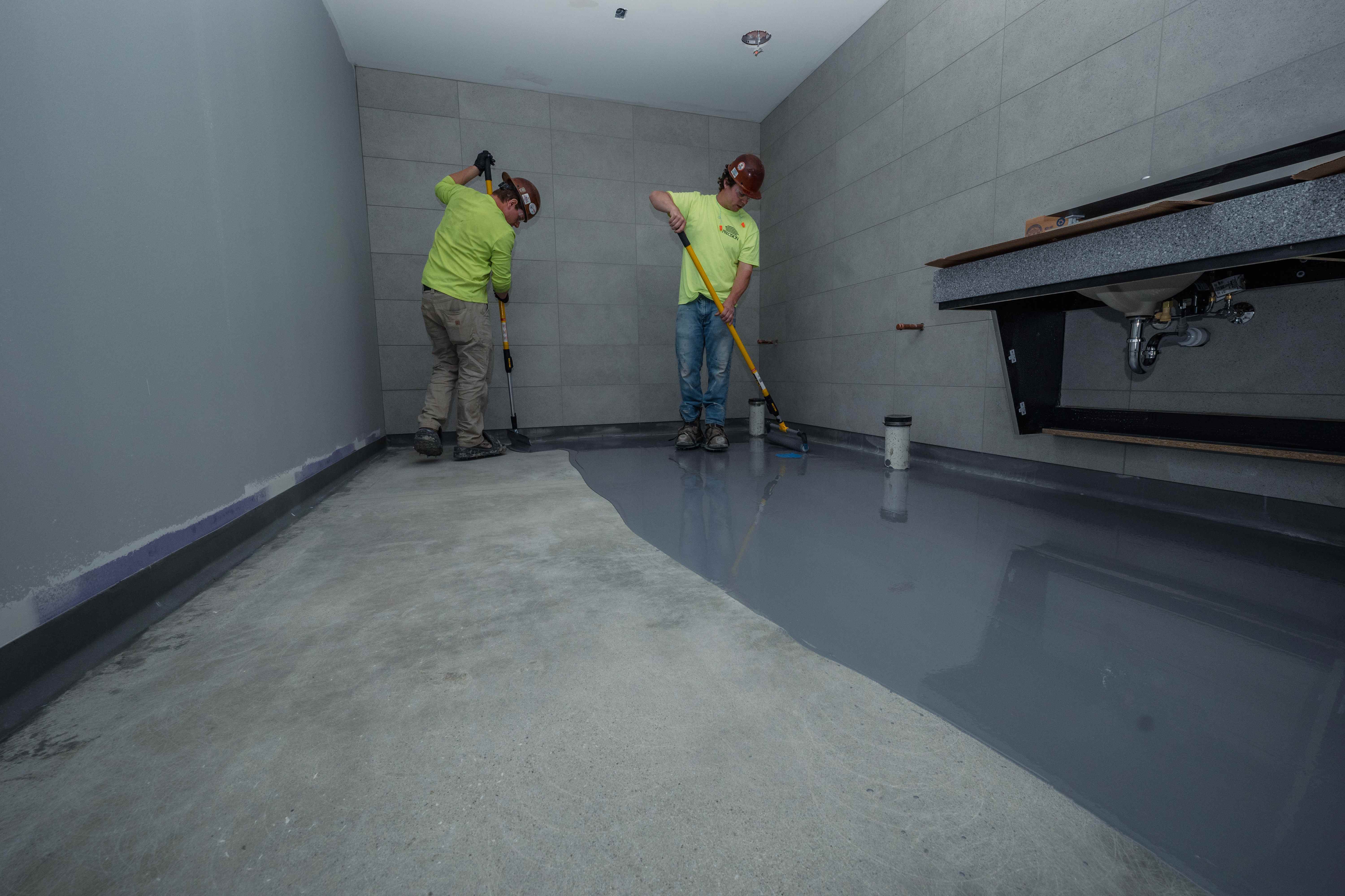 Precision ProFloor tradesmen applying a self-leveling epoxy floor coating on site